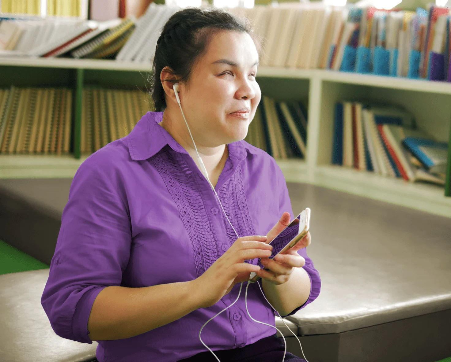 A person wearing headphones plugged into a smartphone