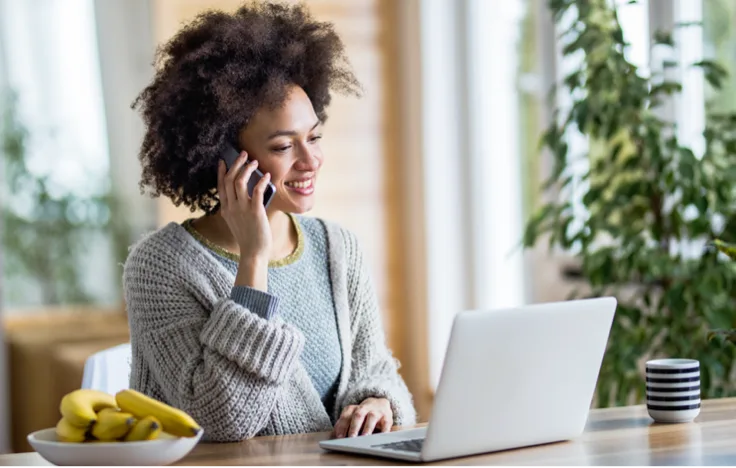 Femme au téléphone tout en travaillant sur son ordinateur portable