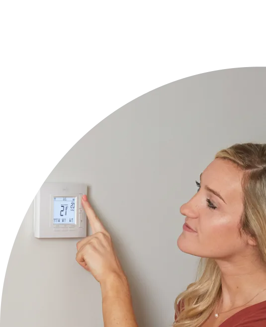 Woman setting a smart thermostat 