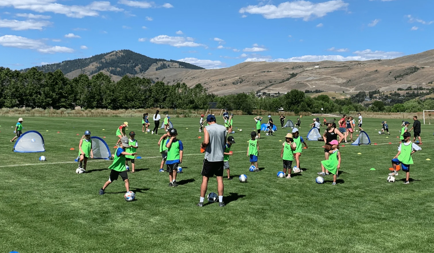 A group of children practicing their footwork on the field at the 2022 Community Soccer Experience.