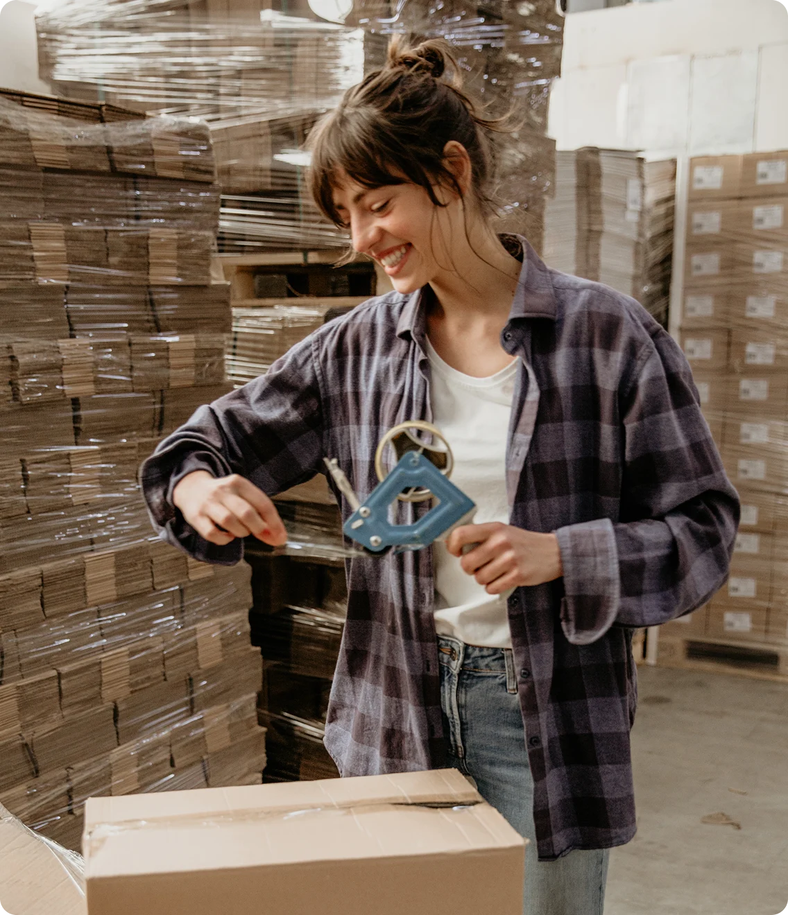 Worker tapes a shipping box in a warehouse.