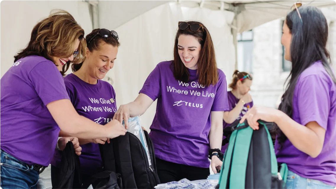 TELUS team members filling backpacks with essential school supplies.