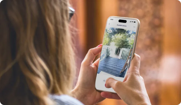 Femme examinant sur l’application TELUS MC+ les images issues d’une sonnette vidéo TELUS pendant sa pause repas à domicile. 