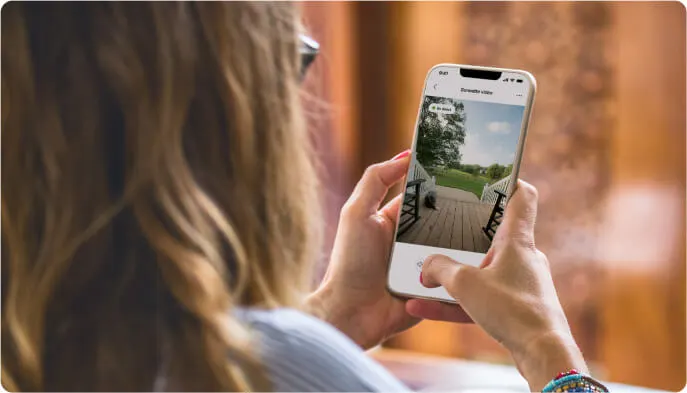 Femme examinant sur l’application TELUS MC+ les images issues d’une sonnette vidéo TELUS pendant sa pause repas à domicile.