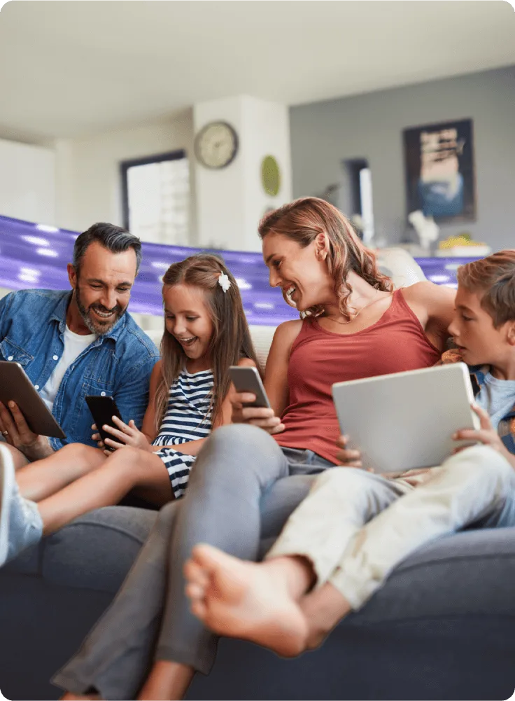 A family enjoys a laugh as they marvel at the incredible new internet speed powering their various devices.