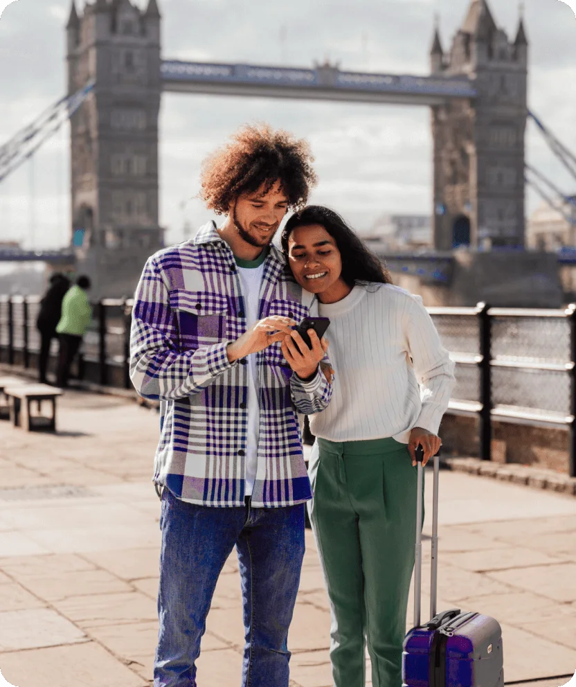 Couple using smartphone while traveling with luggage