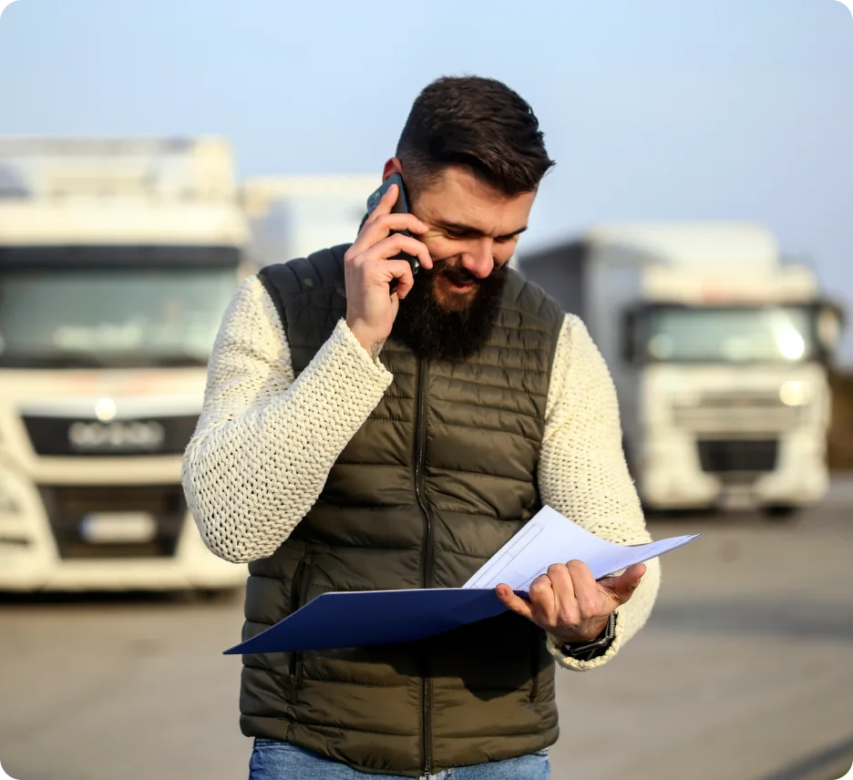 A driver in front of trucks talking on the phone.
