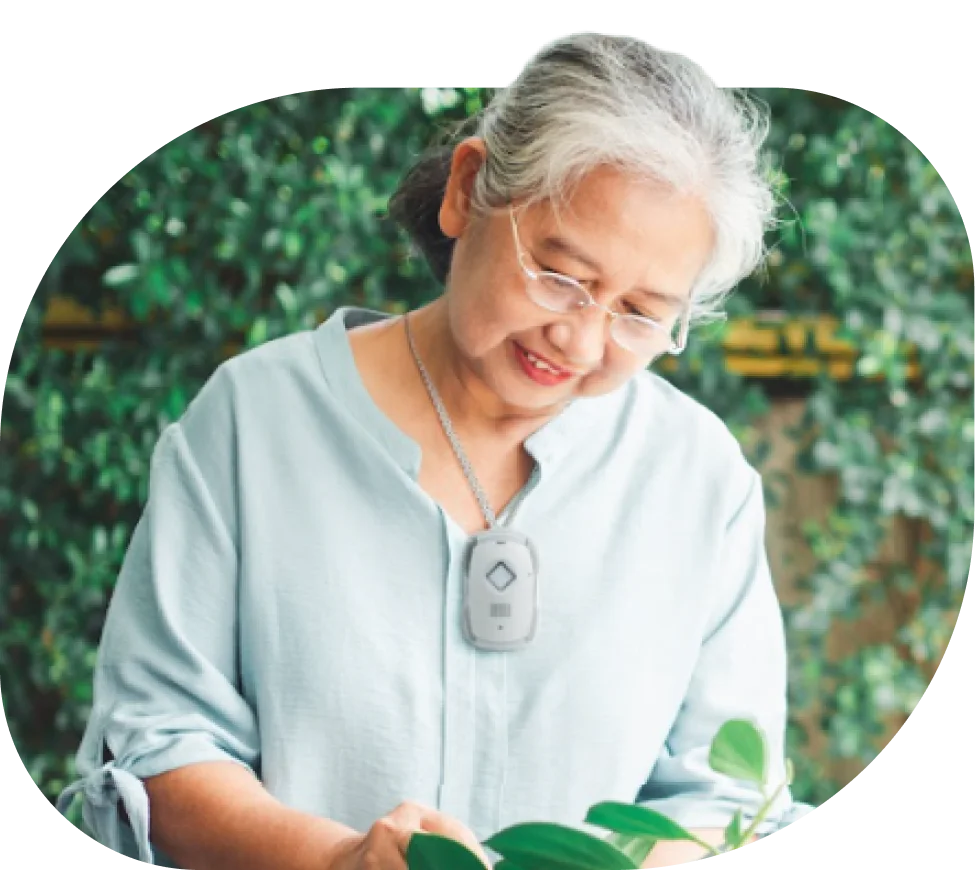 A older adult woman tending to a plant sitting on a table in a garden