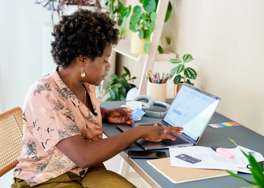 A woman enters her credit card information, as prompted by a screen on her laptop.