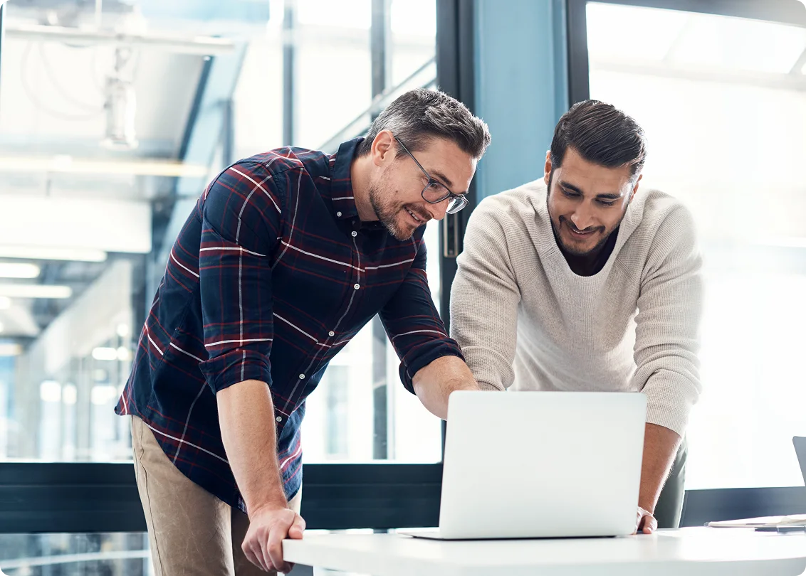 Two colleagues collaborating on a laptop in a modern office.