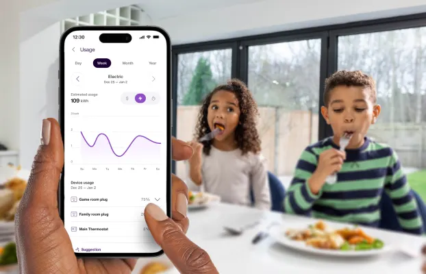 Personne tenant à la main, pendant le petit-déjeuner des enfants, un appareil où sa consommation et ses habitudes en la matière s’affichent dans l’application TELUS MC+. 