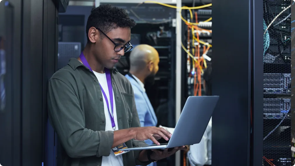 Person in a server room using a laptop.