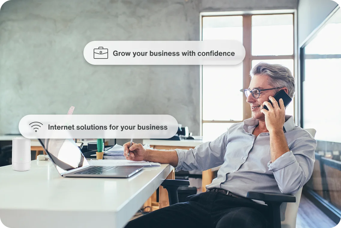 Business owner using laptop in modern workspace with text bubbles promoting fast, reliable internet