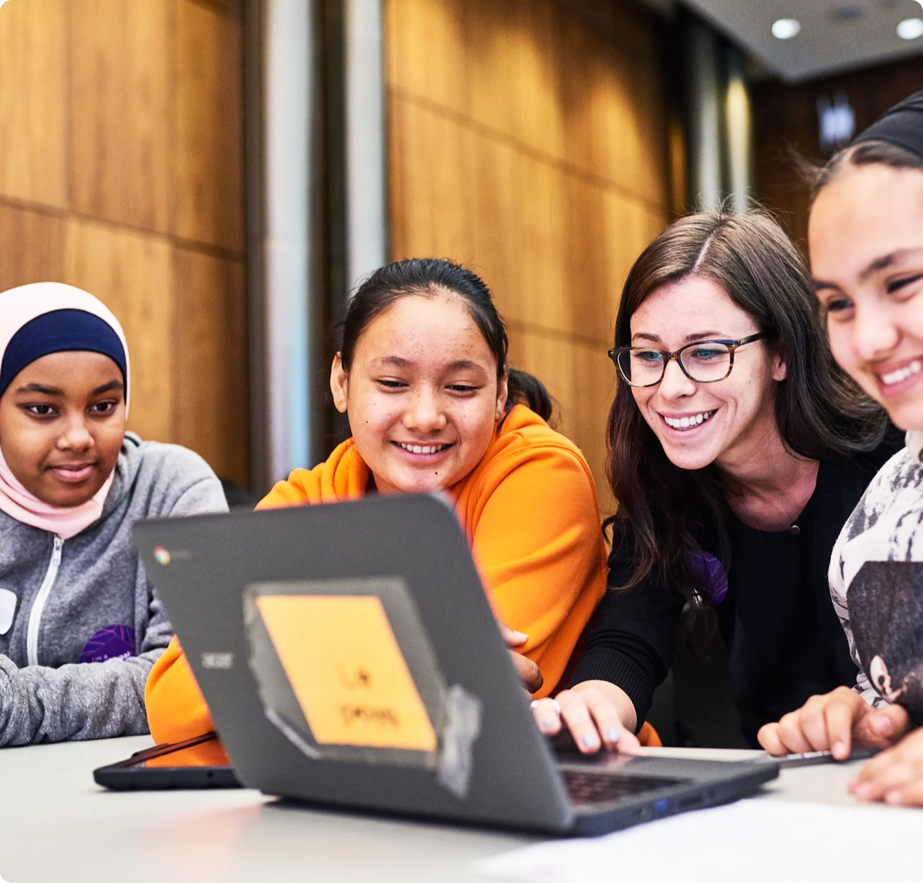 A diverse group of young women gathering around a laptop