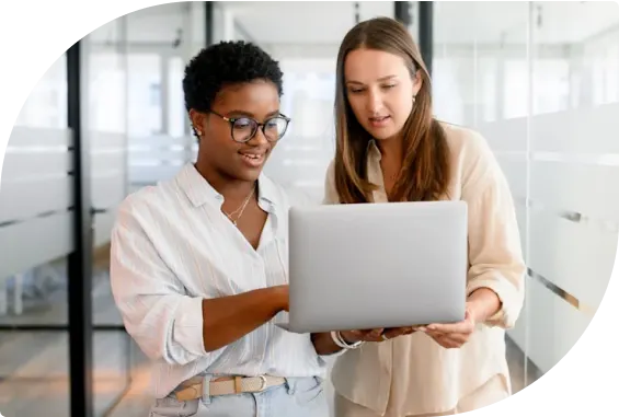 Two professionals reviewing information on a laptop in a modern office, symbolizing seamless collaboration and managed network support across Canada from coast to coast.