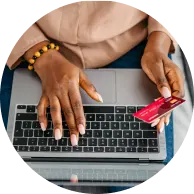 Vue du dessus d’une personne tenant sa carte de crédit et tapant sur un ordinateur portable.