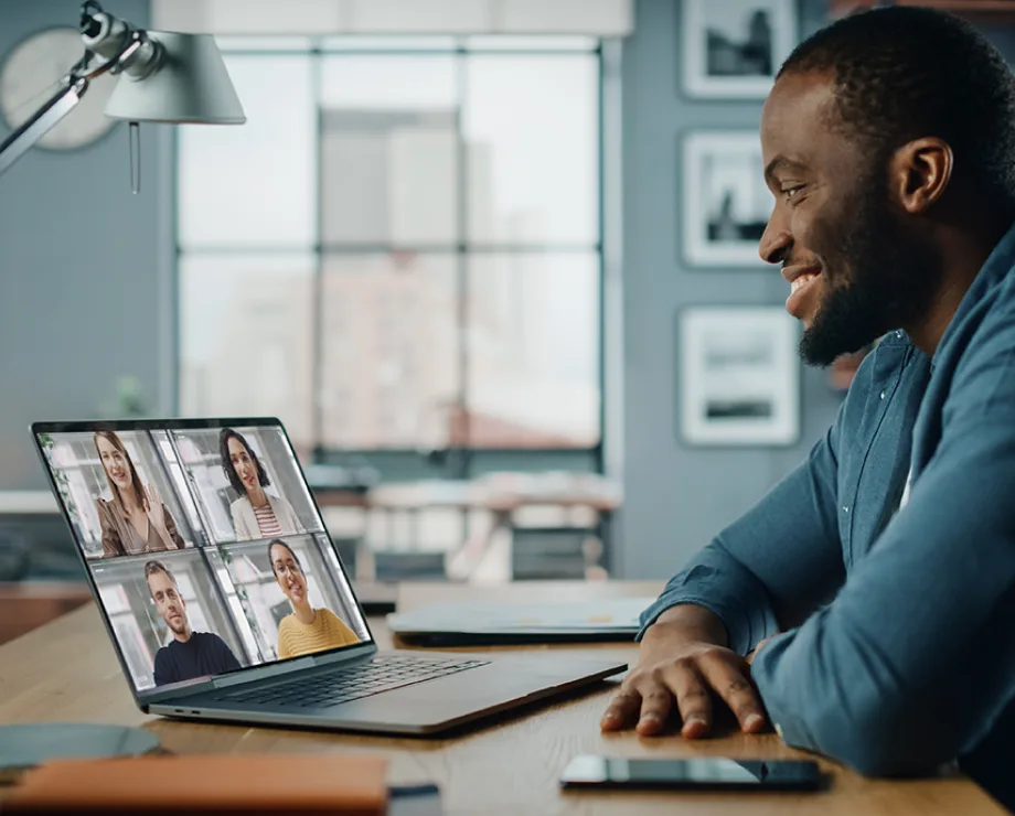 Man seated in front of laptop on a group call, signifying the global scale of Microsoft 365 and Direct Routing from TELUS.