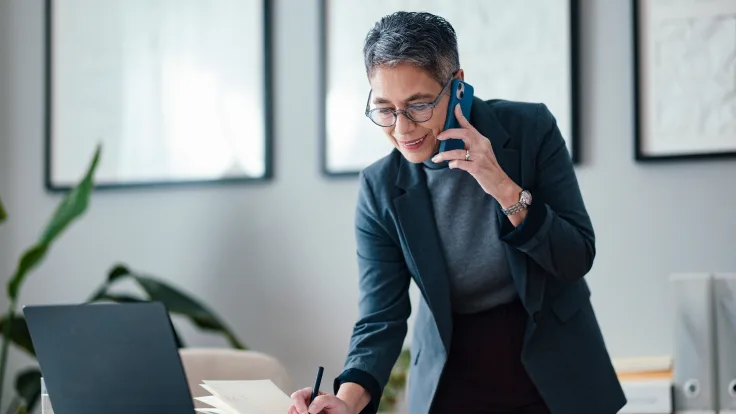 Professional on a phone call while working at a laptop.