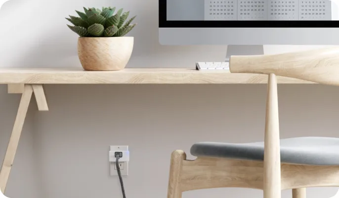 A home office’s computer is plugged in with a smart plug.
