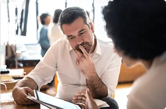 Two professionals in discussion over a digital tablet, symbolizing collaboration and decision-making in the evolving SASE landscape.