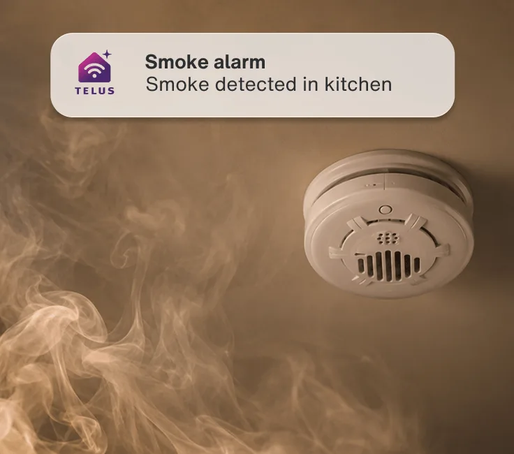 Smoke twirls towards an activated smoke detector. An app alert reads: ”Smoke alarm - Smoke detected in kitchen”