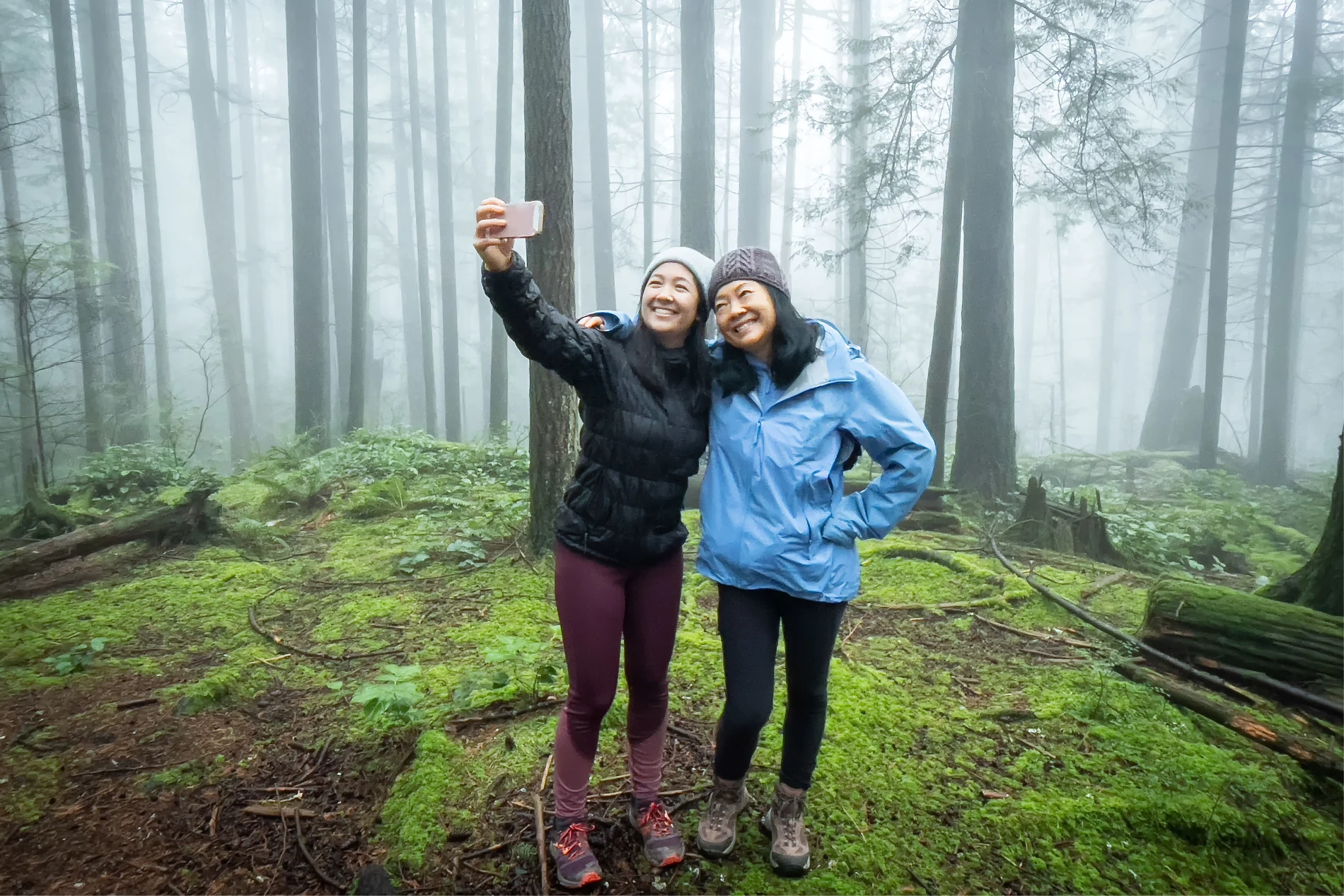 Two women taking a selfie while standing in a forest