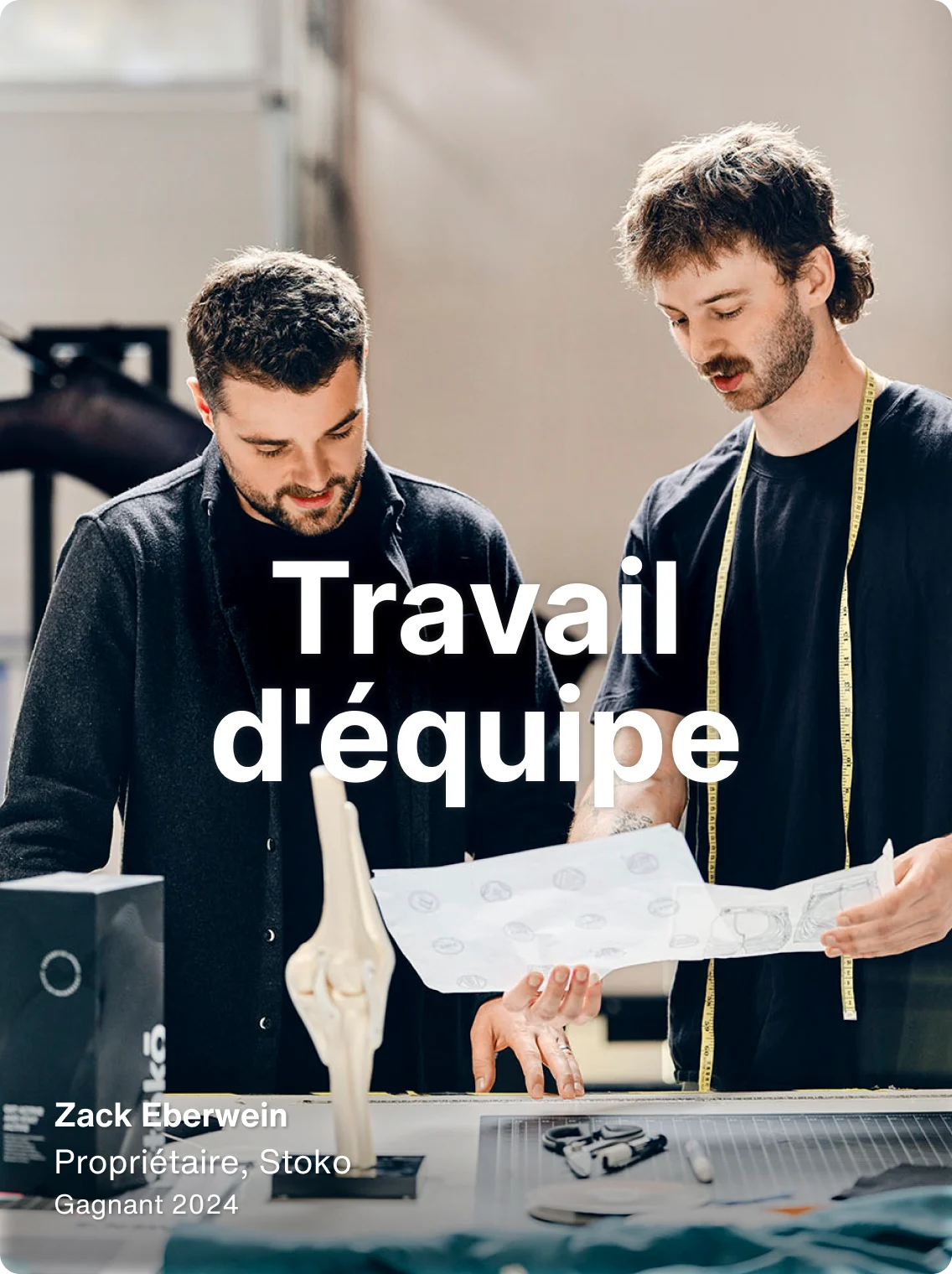 Zack Eberwein, propriétaire de Stoko, examine des conceptions de produits sur lesquelles le mot « Travail d'équipe » est superposé.