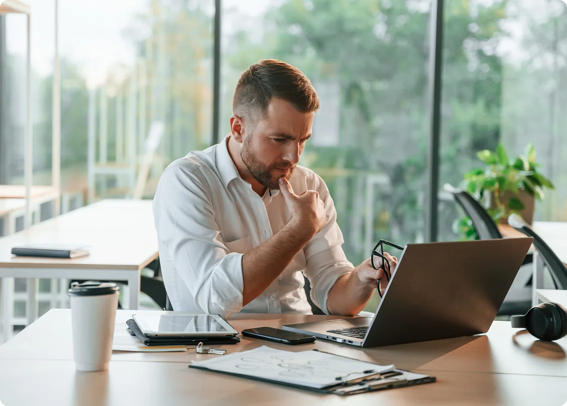 Professional reviewing data and working on laptop at office desk.