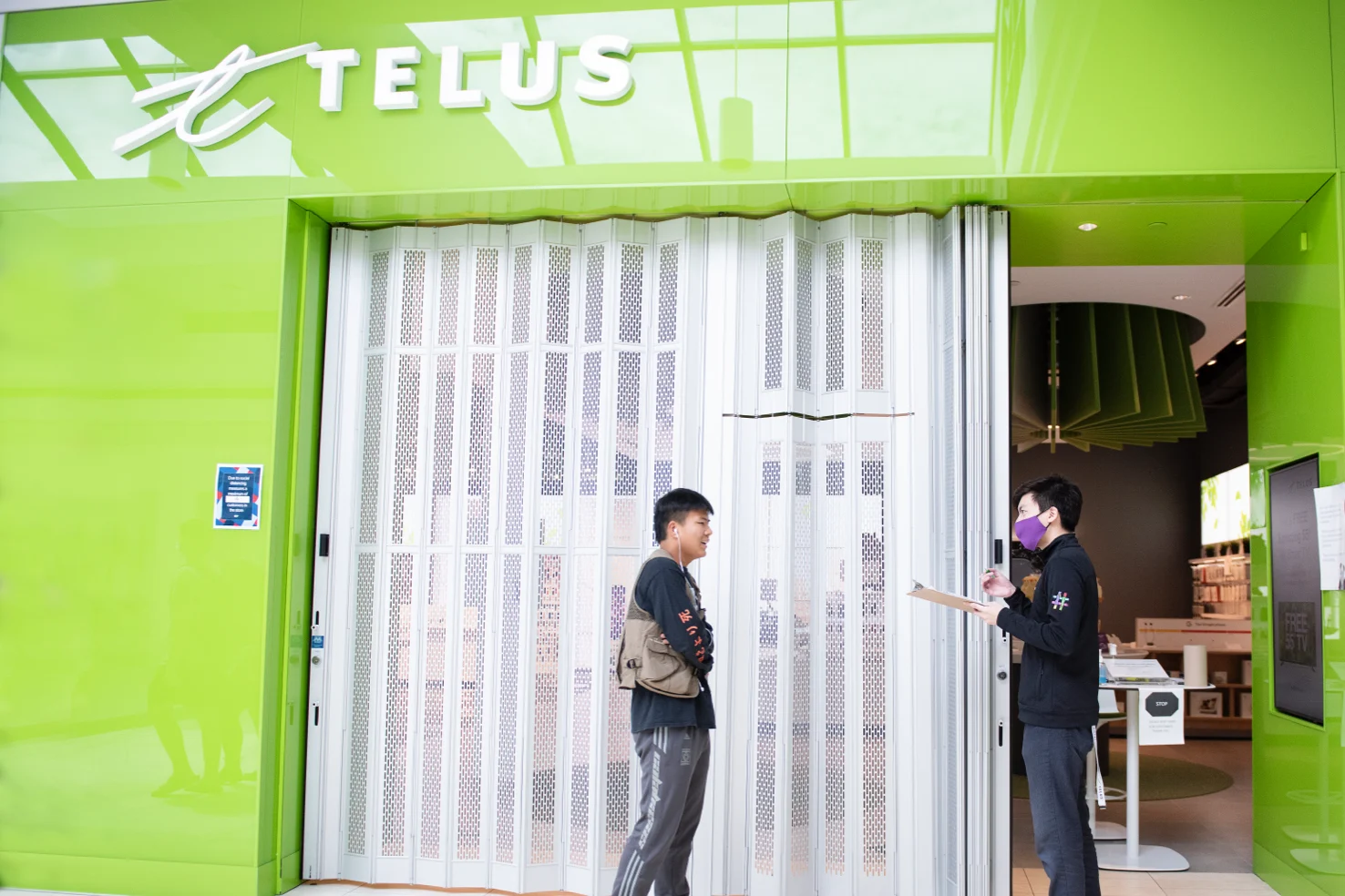 A TELUS employee greets a customer at the entrance to one of our retail stores.
