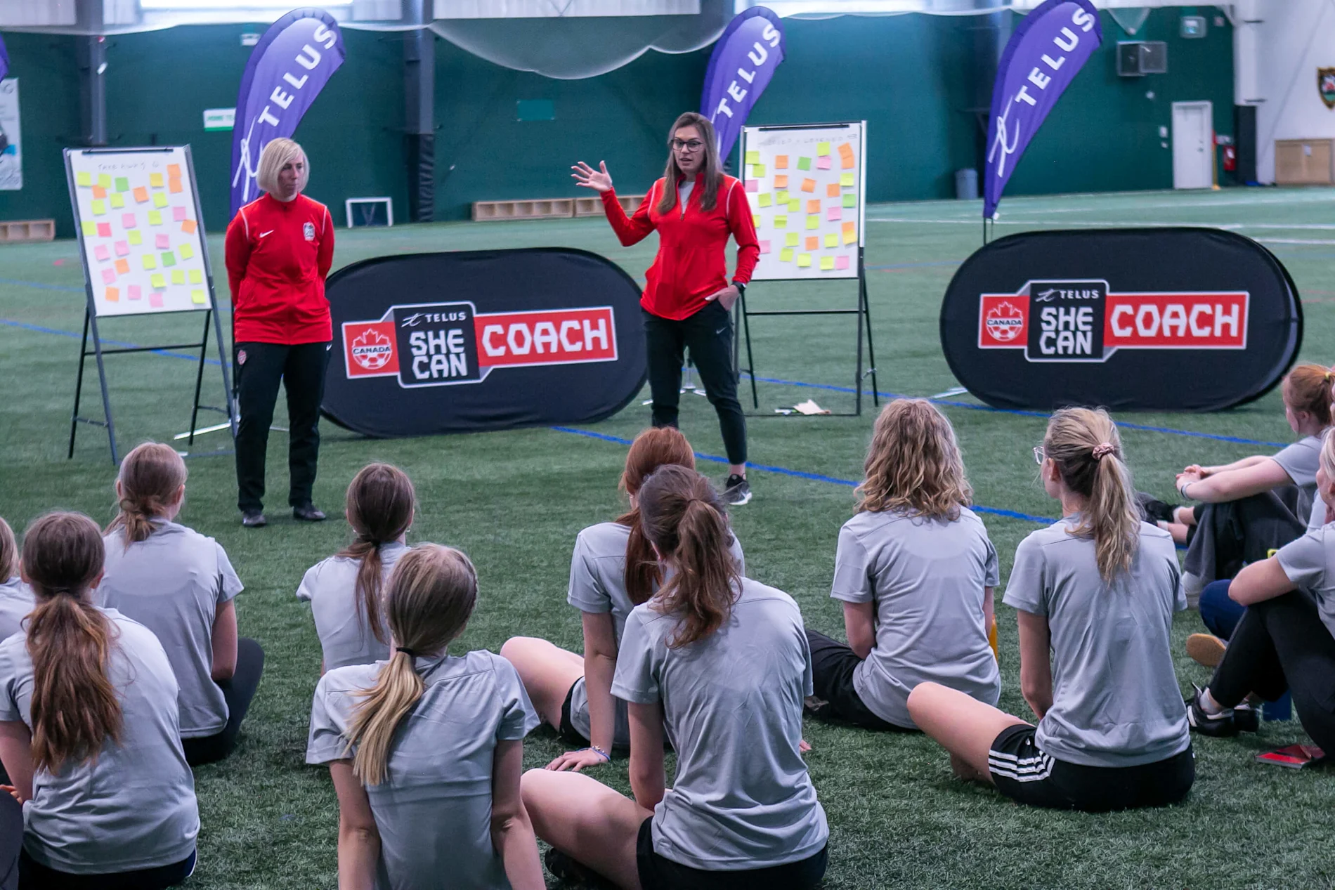 A woman coaching while facing the soccer field.