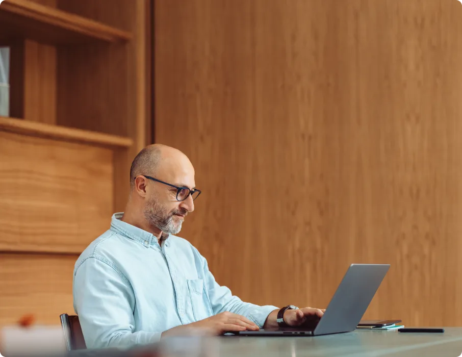 A professional works on a laptop at a desk.