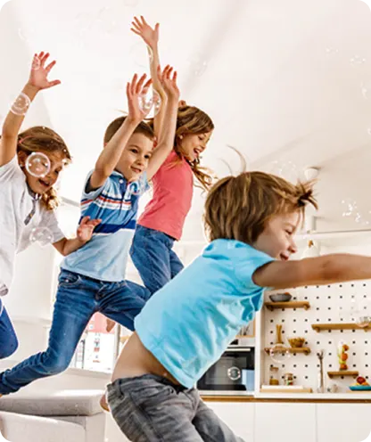 Children jumping on couch in bright living room