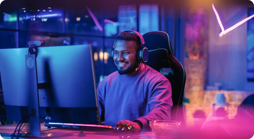 A smiling man seated in front of a large computer monitor