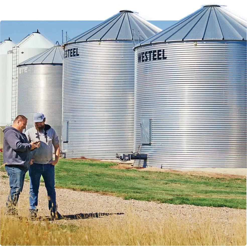 Two farmers monitoring real-time activity on the field on their smartphone.