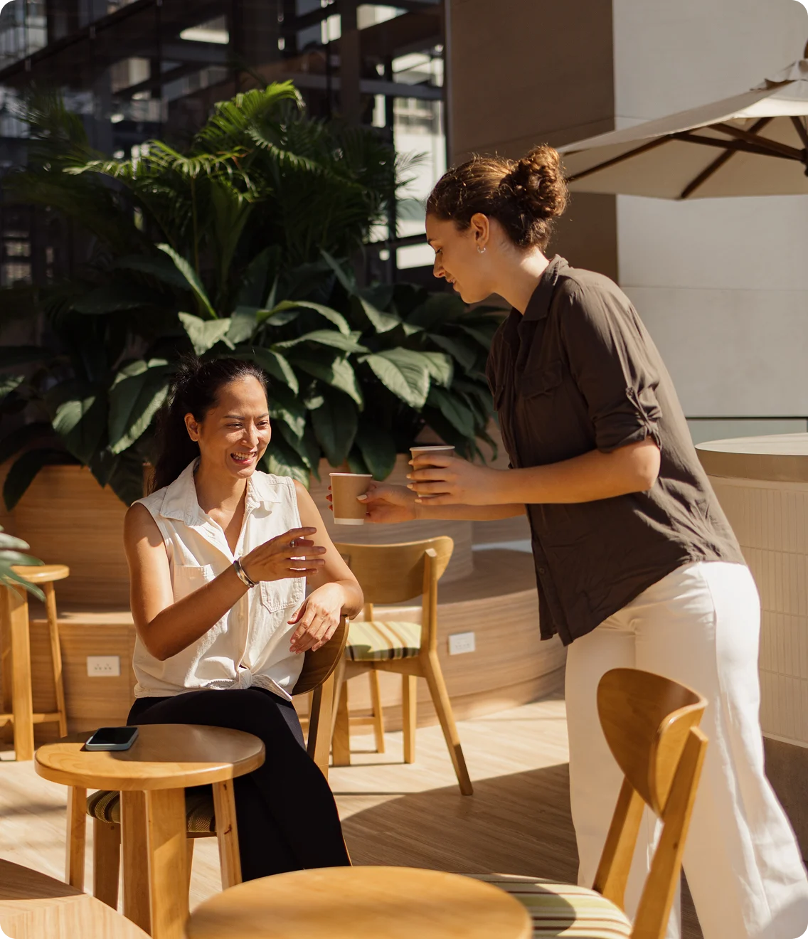 Restaurant staff serving a happy customer seated in modern cafe
