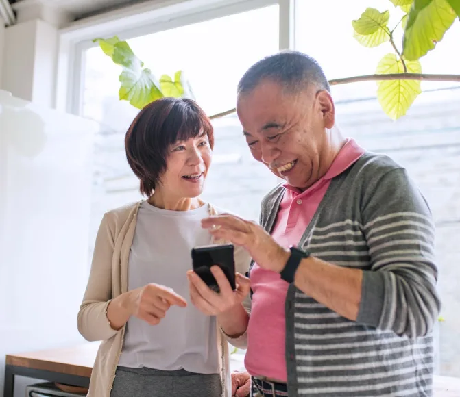 An older couple smiling while viewing a smartphone