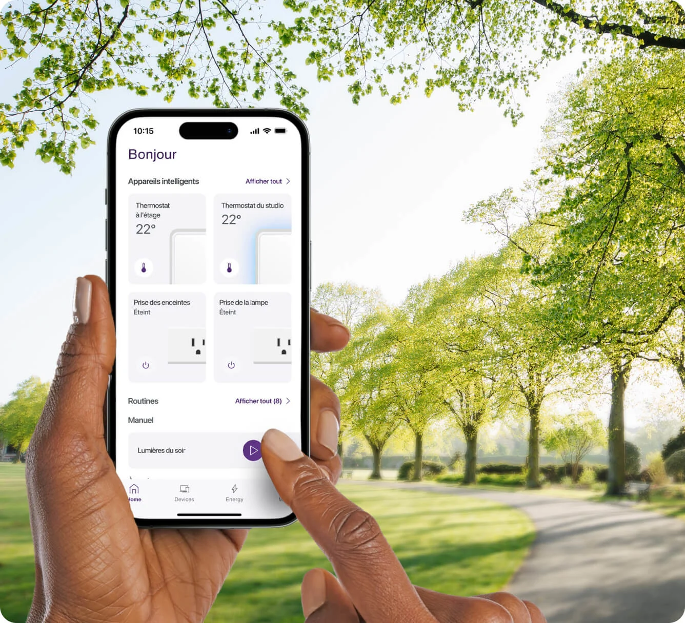 Personne marchant dans un parc avec à la main un appareil sur lequel s’affichent les fonctionnalités de contrôle des thermostats, des prises intelligentes et des horaires de l’application TELUS MC+. 