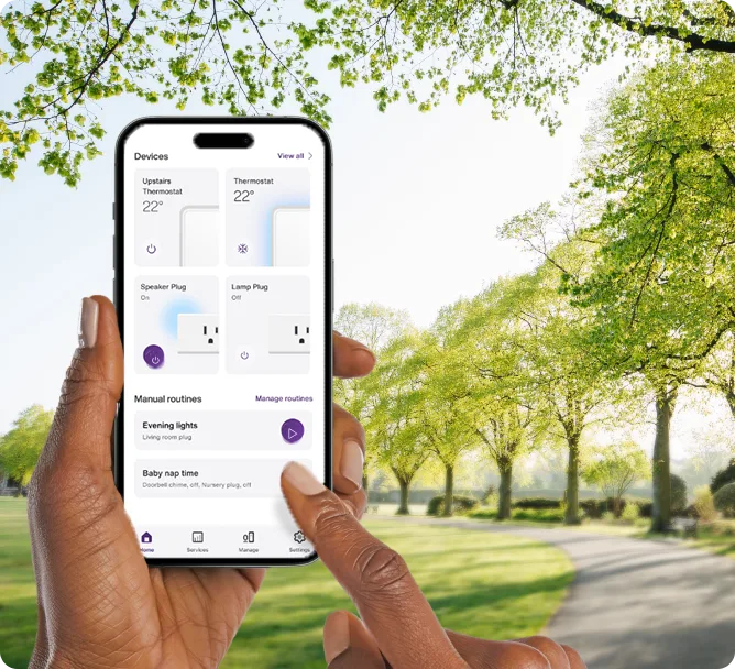 A hand holds the TELUS SmartHome+ app while out on a walk in the park showing the control of thermostats, smartplugs and routines.