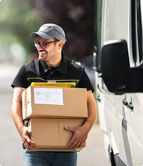 Delivery driver carrying packages near delivery van.