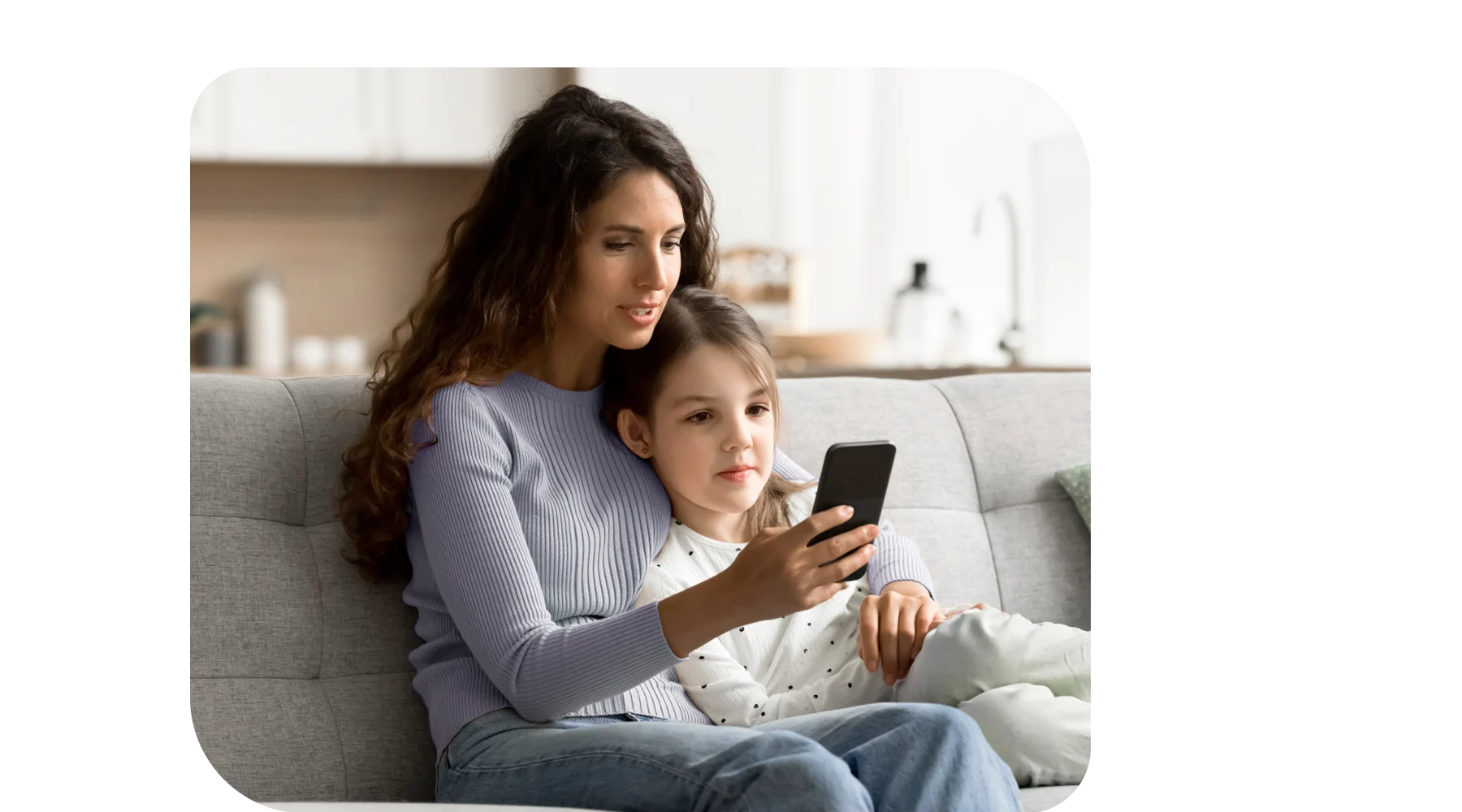 Young mom at home with her toddler, engaging with a smartphone.