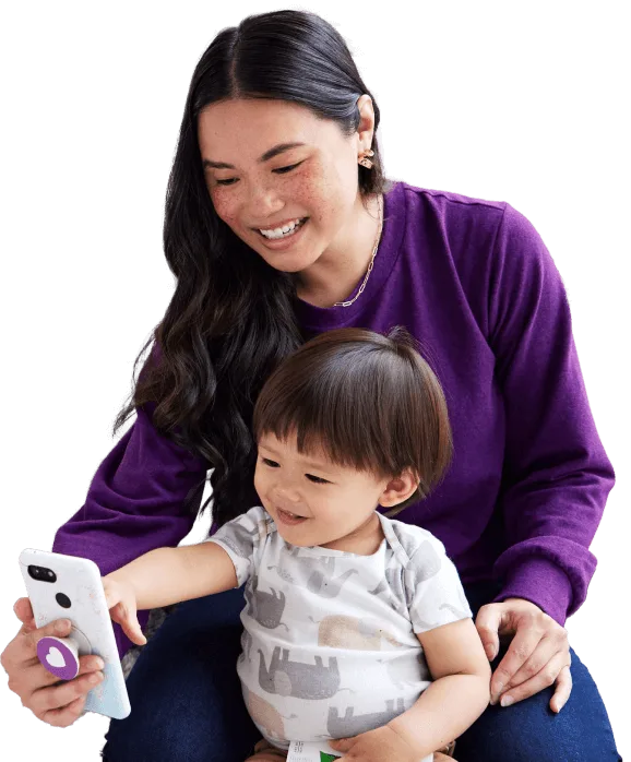 Young mom at home with her toddler, engaging with a smartphone.