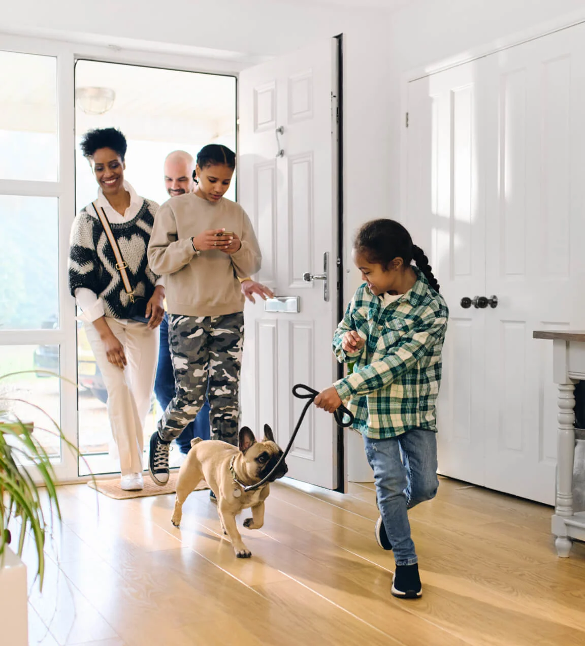 A TELUS Indoor Camera captures a family coming home from walking the dog at the front door. 