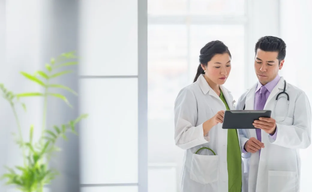 Two medical professionals having a discussion over details displayed on a tablet