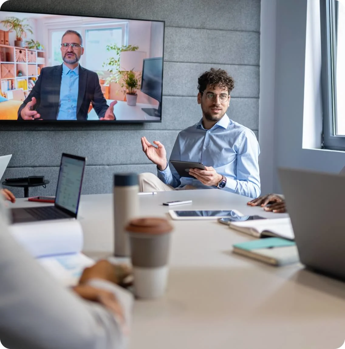 Business professionals gathered in a meeting room with a laptop and a television for a presentation or discussion.