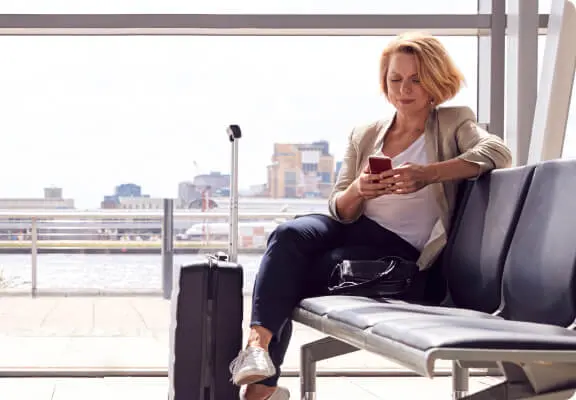 Femme qui relaxe avec son téléphone dans le salon d’un aéroport