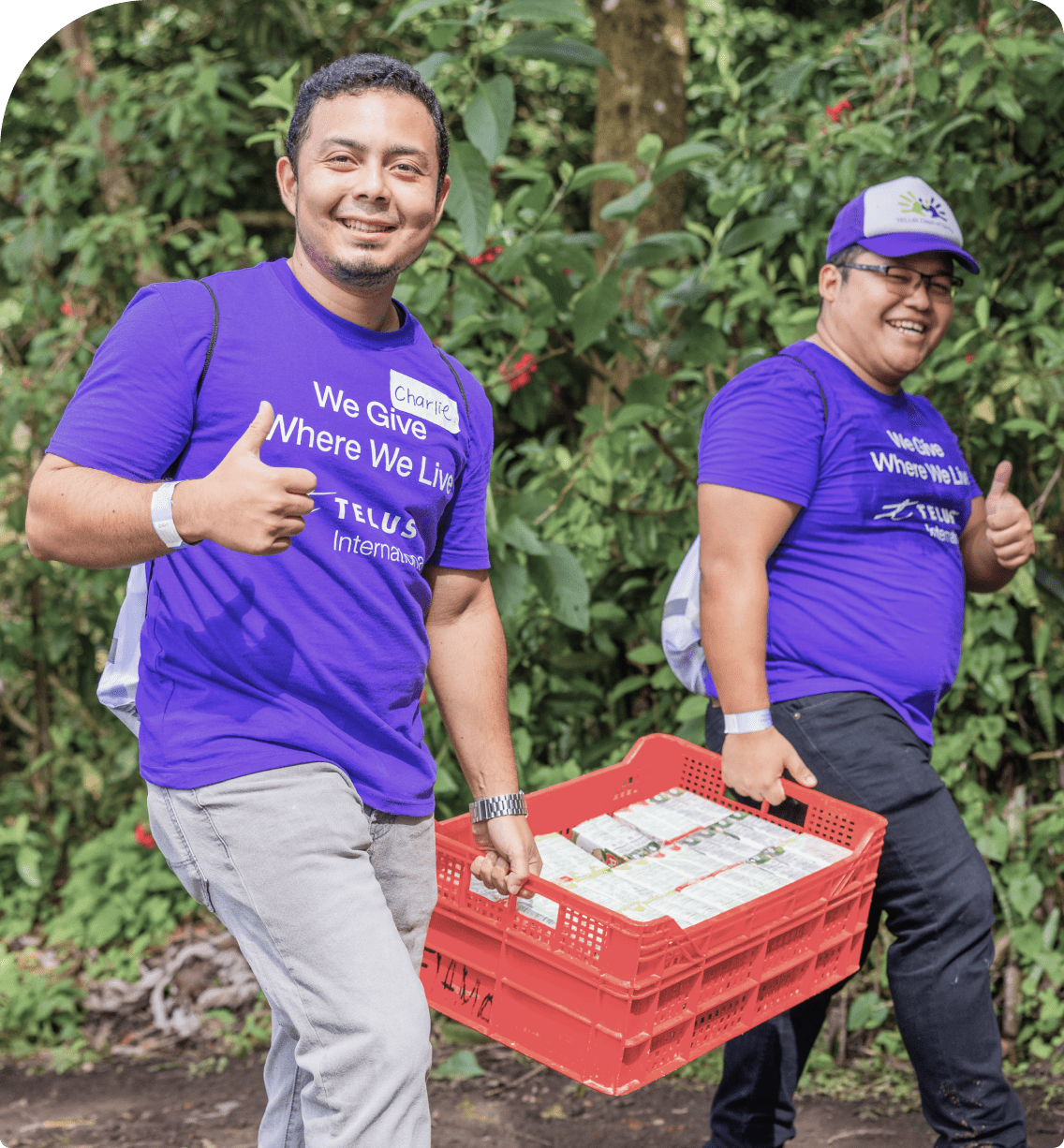 Two TELUS team members carrying a crate of groceries.