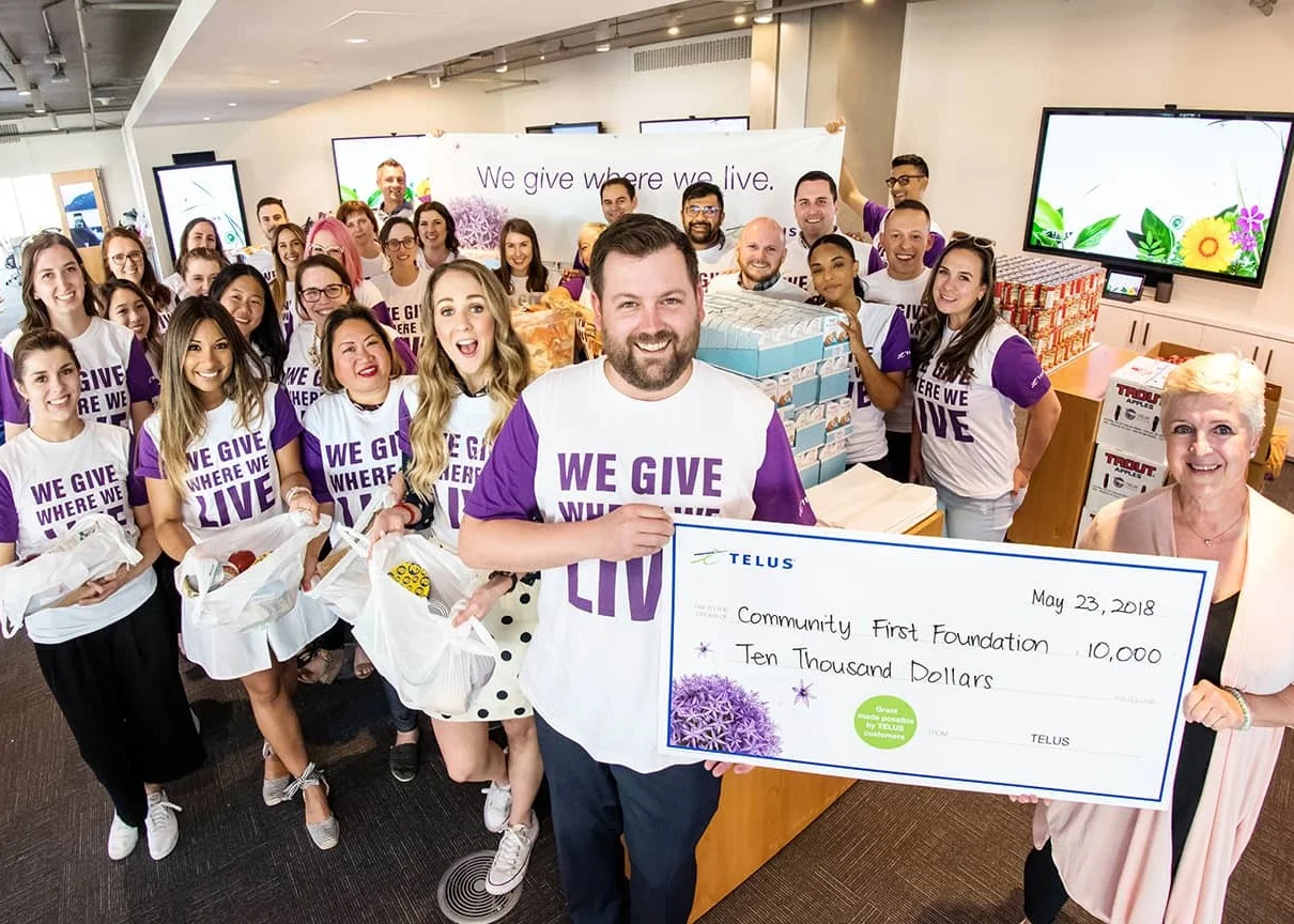 A group of TELUS volunteers displaying a large donation cheque