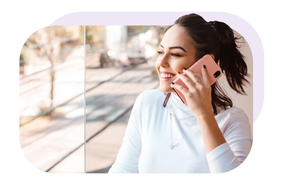A woman is smiling while talking on the phone. 