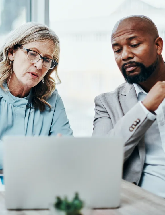 Two people sitting together while looking at a laptop.