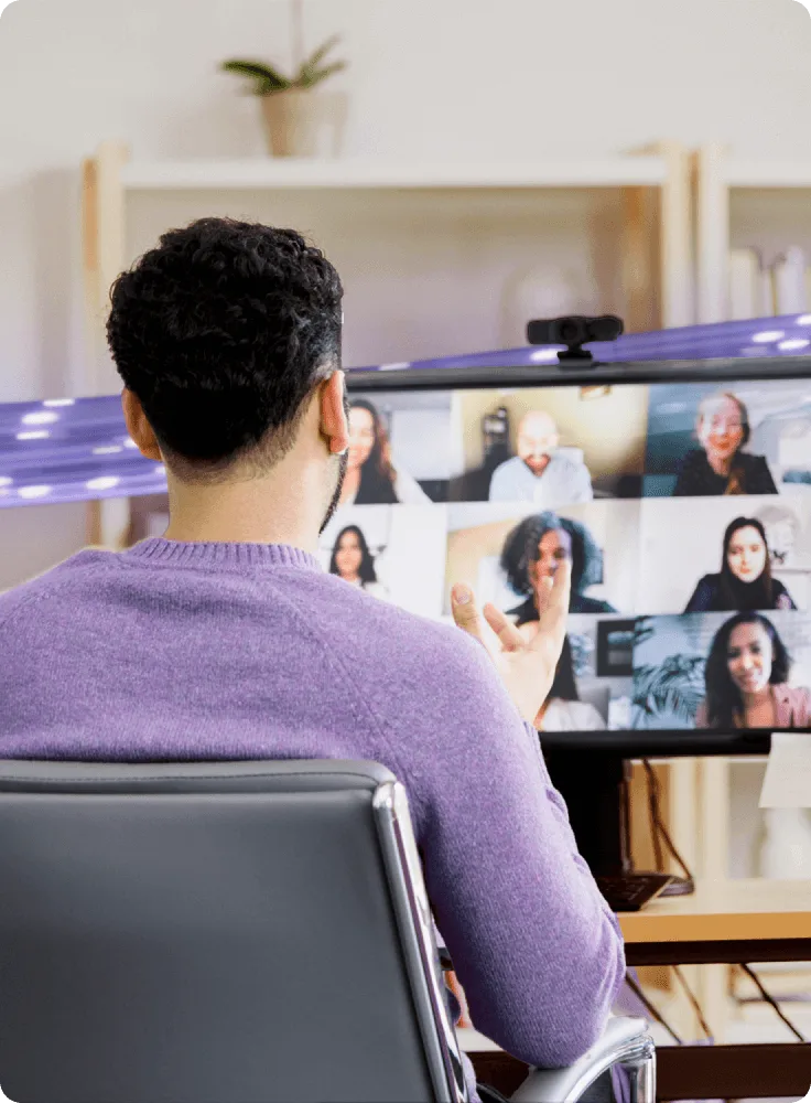 A person looks at a computer monitor and enjoys the crystal clear audio and video of his 5-gigabit-powered group video conference.